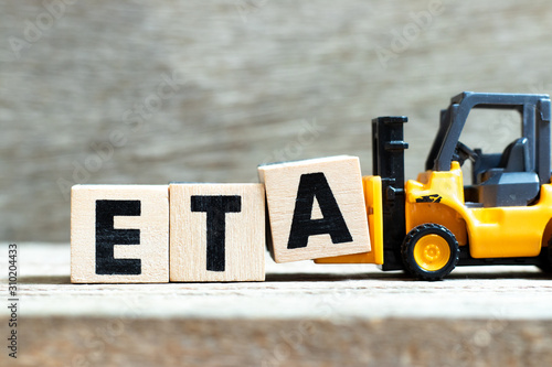 Toy forklift hold letter block a to complete word ETA (abbreviation of estimated time of arrival) on wood background