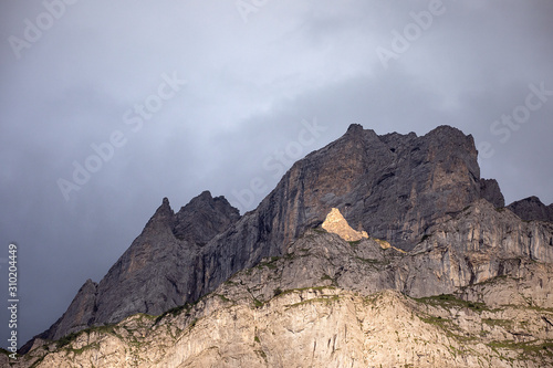 Scenic high rocky mountain peak in sunset light. Shadow and light. Sloping inaccessible surface of Rocky mountain. Dramatic overcast sky. Alpine landscape romantic, Switzerland.