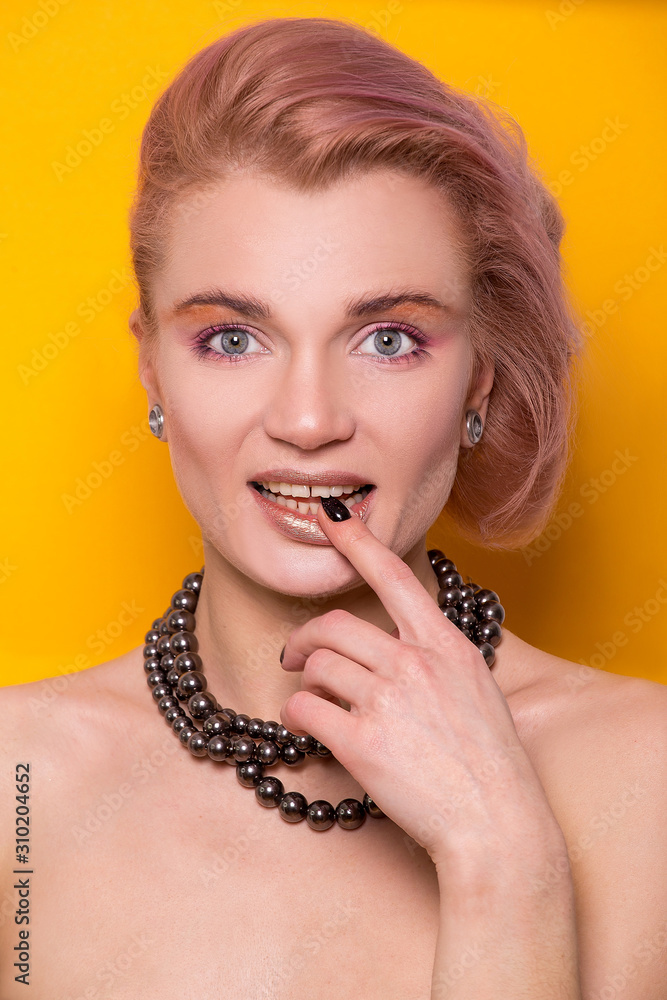 Shiny golden make-up on a beautiful young European model girl isolated on an orange background in the photo studio