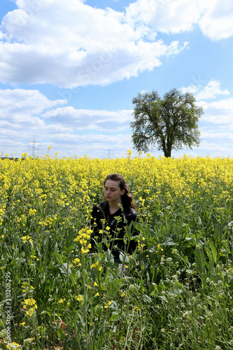 Sad teenage girl in a field of flowers in Germany.