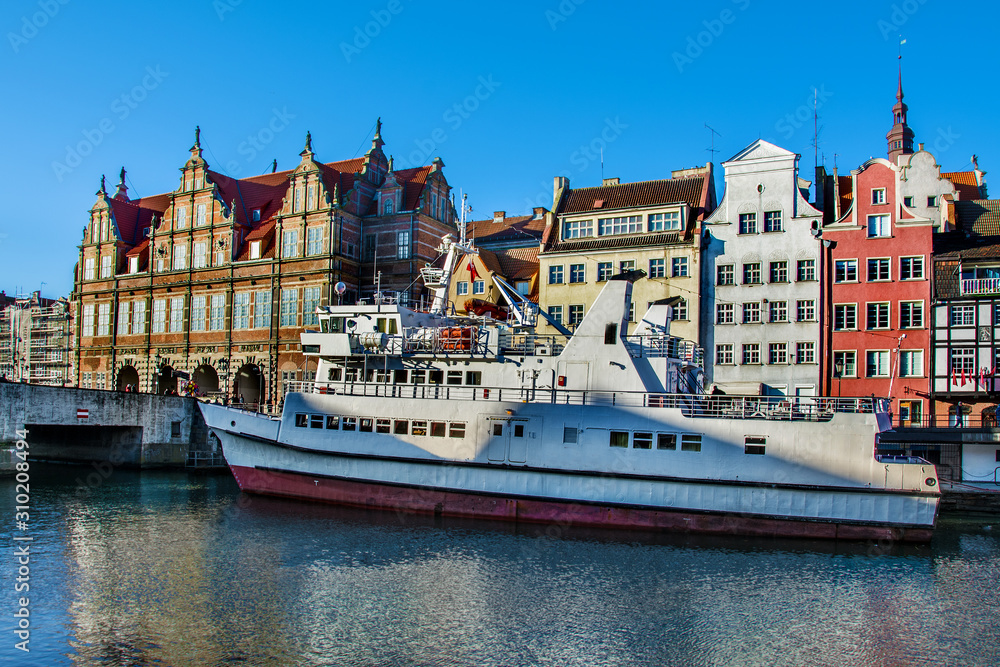 Tourist ship and historic houses next to Motlawa river in port of Gdansk, Baltic Sea, Poland.