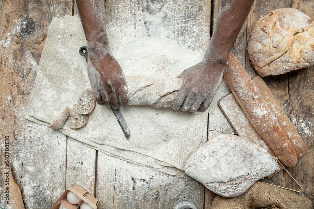 Top view of african-american man cooks fresh cereal, bread, bran on wooden table. Tasty eating, nutrition, craft product. Gluten-free food, healthy lifestyle, organic and safe manufacture. Handmade. Top view of african-american man cooks fresh cereal, bread, bran on wooden table. Tasty eating, nutrition, craft product. Gluten-free food, healthy lifestyle, organic and safe manufacture. Handmade.