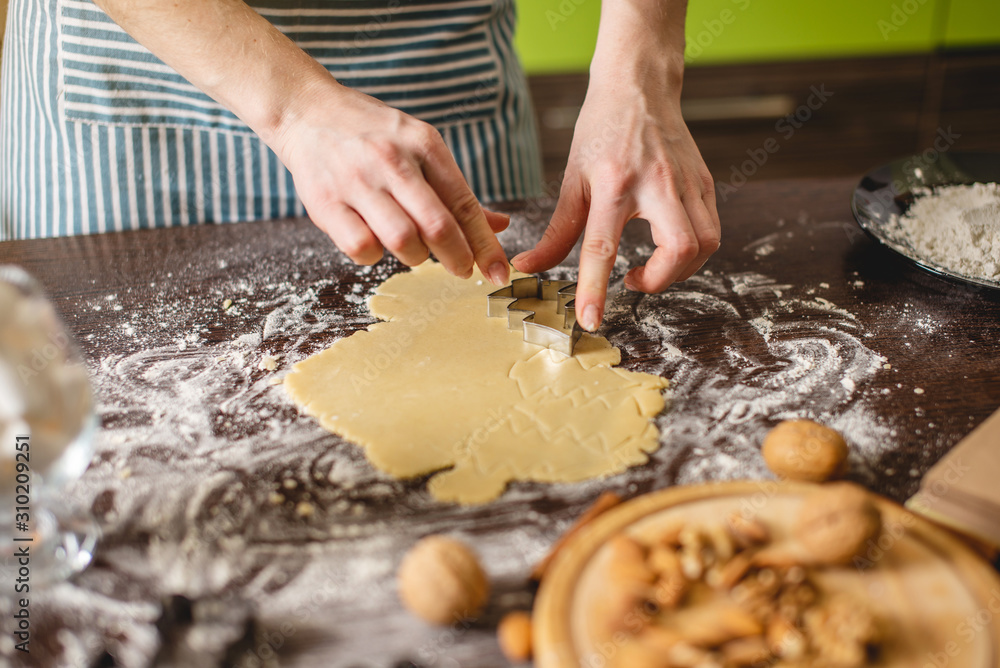 Cook housewife making Christmas cookies at home on a colorful kitchen. Hands making dough the shape of Christmas trees Cook housewife making Christmas cookies at home on a colorful kitchen. Hands making dough the shape of Christmas trees