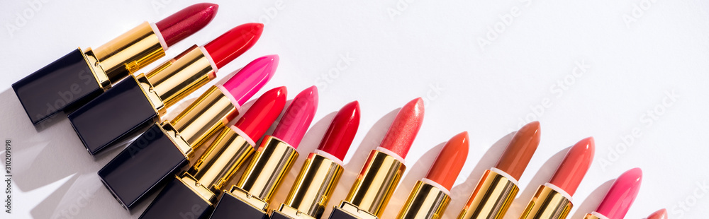 top view of assorted lipsticks in luxury tubes on white background, panoramic shot - obrazy, fototapety, plakaty 