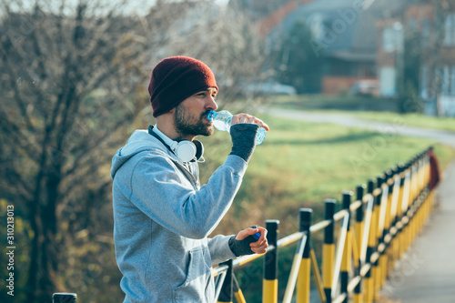 handsome young man jogging outdoor, drinking water