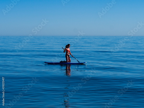 Asian woman kneeling on standup paddle board Sea of Cortez.