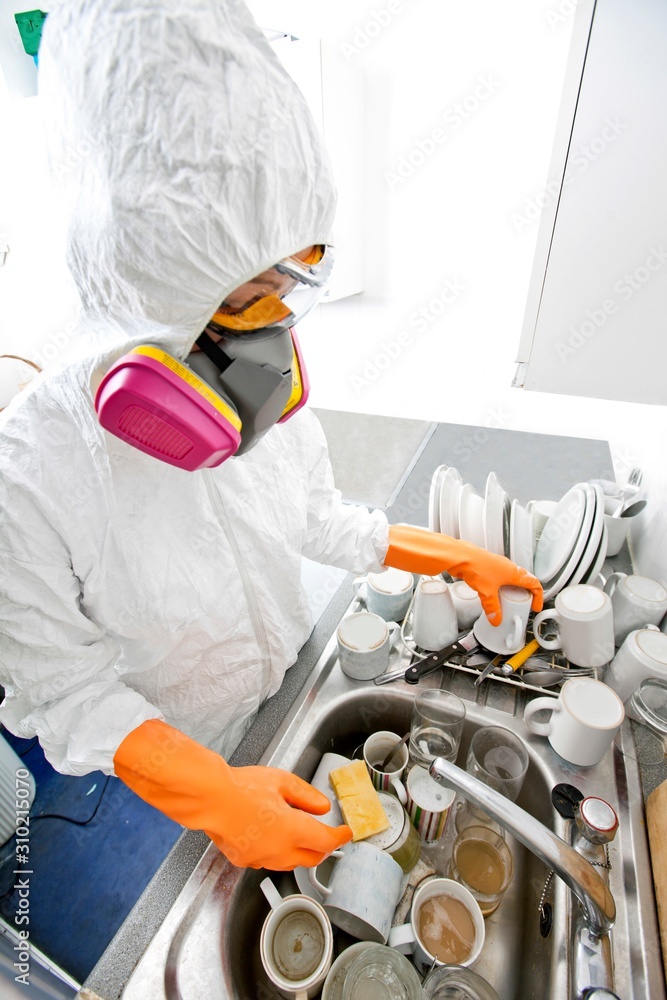 High angle view of woman in gas mask washing utensil at kitchen sink