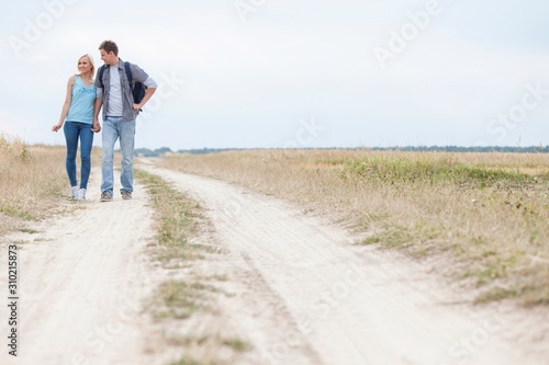 Full length of young hiking couple standing on trail at field