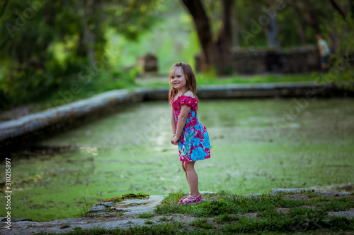 Girl playing in nature near the lake covered with green algae.