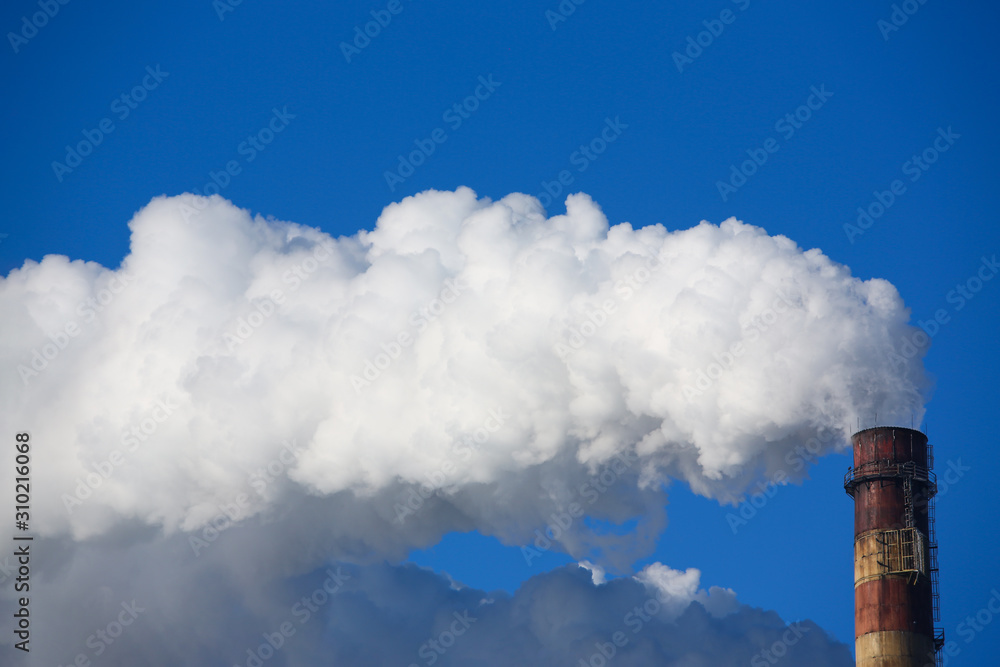 White smoke comes from pipes against blue sky White smoke comes from pipes against blue sky