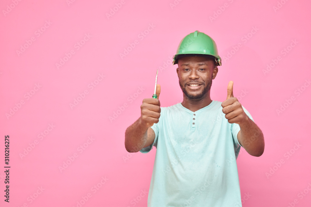 handsome excited young black man wearing a hard hat and holding a screwdriver feeling excited giving thumbs up gesture handsome excited young black man wearing a hard hat and holding a screwdriver feeling excited giving thumbs up gesture