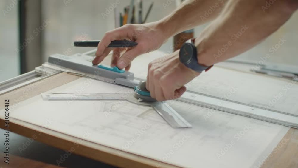 Engineer draws buildings on the table using a pencil and ruler. An architect creates a building design on paper using a marker and ruler Engineer draws buildings on the table using a pencil and ruler. An architect creates a building design on paper using a marker and ruler