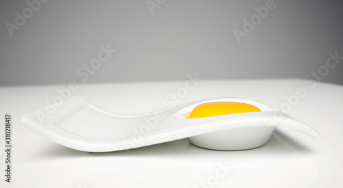 White dish with egg yolk. White and yellow. Close up picture. Studio still life 