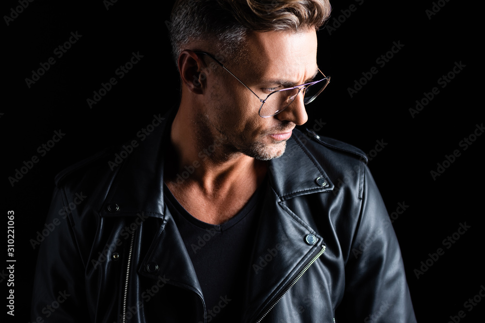 Fototapeta premium Stylish man in leather jacket looking away isolated on black