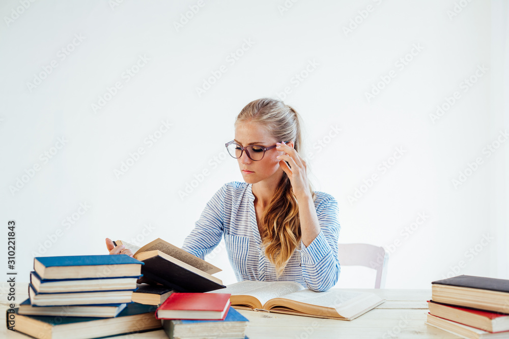 female teacher sitting at a table of many books Office