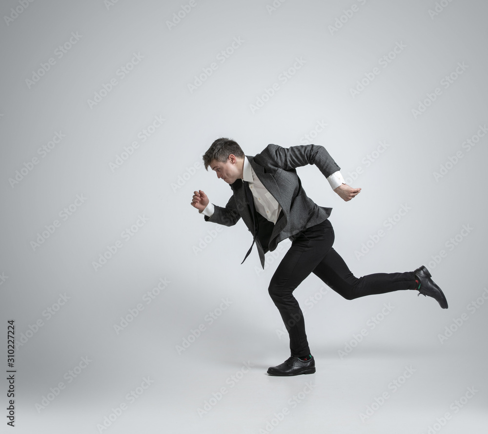 Hurry up, you're wild and young. Caucasian man in office clothes running like a professional sportsman on grey background. Businessman training in motion, action. Sport, healthy lifestyle concept. Hurry up, you're wild and young. Caucasian man in office clothes running like a professional sportsman on grey background. Businessman training in motion, action. Sport, healthy lifestyle concept.