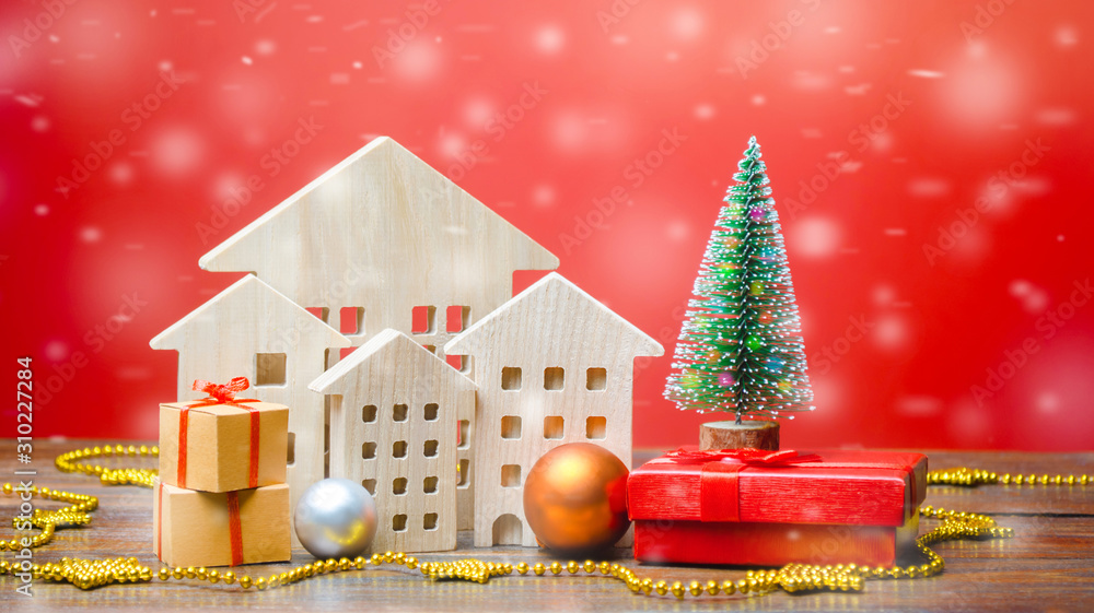 Christmas tree, miniature wooden houses and gifts. New Year or Xmas winter holiday. Decoration, celebration. The concept of the beginning of the new year. Snow, snowfall. Real estate sale