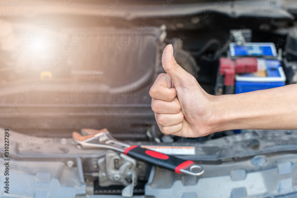 Automotive mechanic show a thumbs up after the car check and repair in workshop. Automotive mechanic show a thumbs up after the car check and repair in workshop.