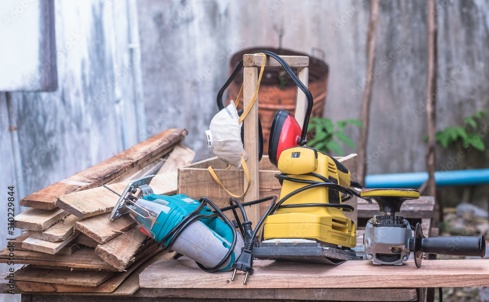 Woodworking power tools including rectangular orbit sander, grinder and jig saw with wooden tool box at outdoor workshop. Woodworking power tools including rectangular orbit sander, grinder and jig saw with wooden tool box at outdoor workshop.