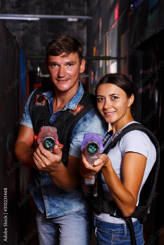 couple holding colored laser guns during laser tag game