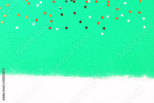 Confetti and snow on green background. Christmas and winter holidays.