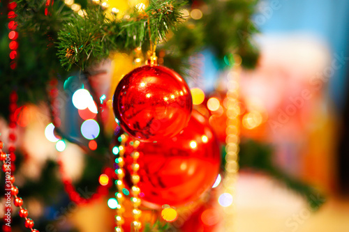 Christmas tree decorations. Decorated Christmas tree with colored red ball, golden bow, pine cones, garland beads, blurred background, shallow depth of field, bokeh