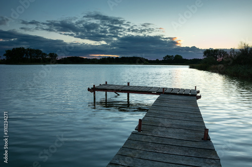 Jetty on a calm lake and clouds, evening view