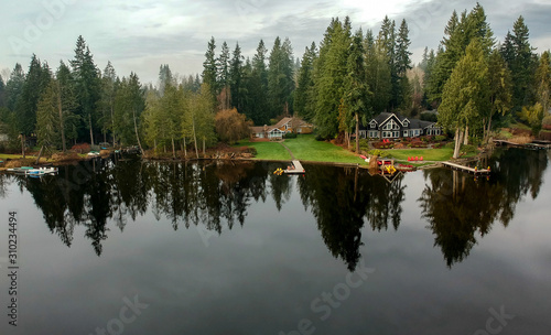 Fototapeta Naklejka Na Ścianę i Meble -  Lovely Lake Joy and the waterfront houses on a fog covered day with the surrounding trees and lingering clouds above reflecting in the water in the pacific northwest.