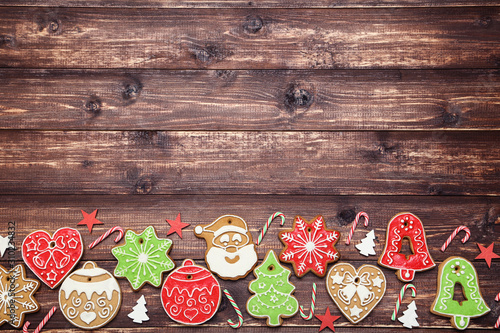 Christmas gingerbread cookies with candies and ornaments on brown wooden table