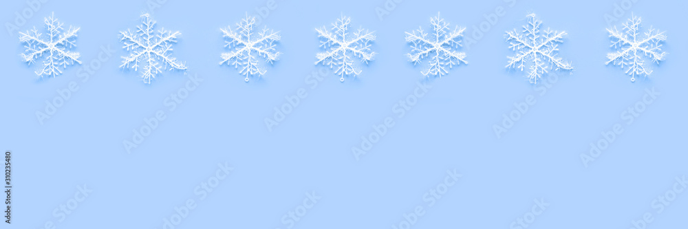 Banner of white snowflakes on blue background with copyspace. Winter holidays concept. New Year and Christmas decoration Banner of white snowflakes on blue background with copyspace. Winter holidays concept. New Year and Christmas decoration