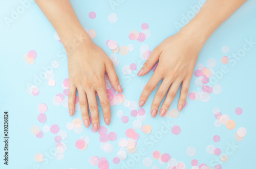 Female hands with a gentle nude manicure on a blue background.