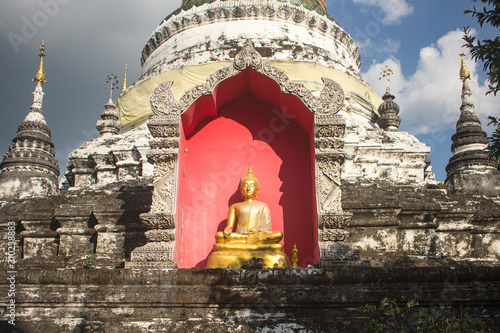 Earth Touching Buddha Sitting statue with golden cloth housed within the chedi of Wat Buppharam, Chiang Mai photo