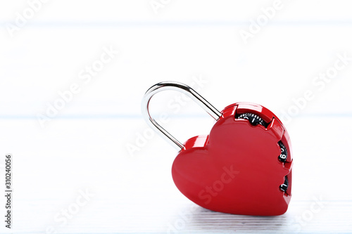 Red heart shaped padlock on wooden table