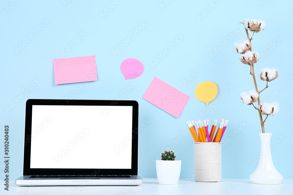 Laptop computer with cactus, pencils and cotton branch on blue background Laptop computer with cactus, pencils and cotton branch on blue background