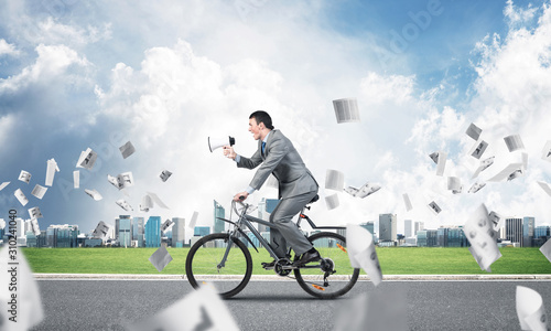 Businessman with megaphone in hand on bike