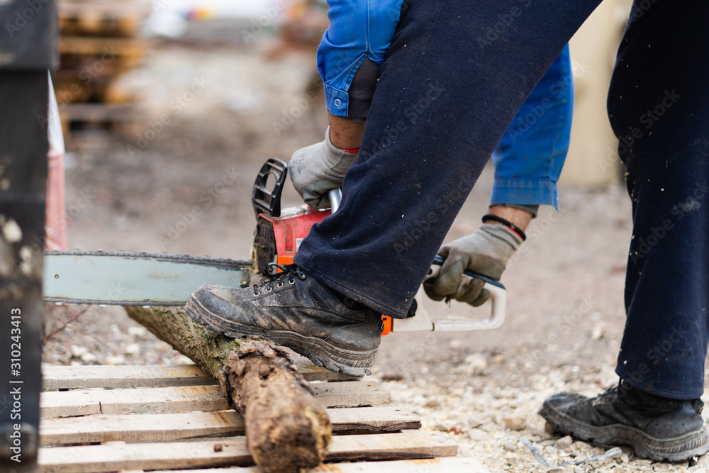 Midsection of man holding the chainsaw cutting wood timber trunk in autumn or winter day in the yard outdoor Midsection of man holding the chainsaw cutting wood timber trunk in autumn or winter day in the yard outdoor