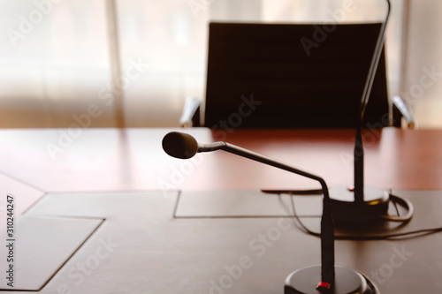 microphone on a wooden table and an empty chair in a boardroom