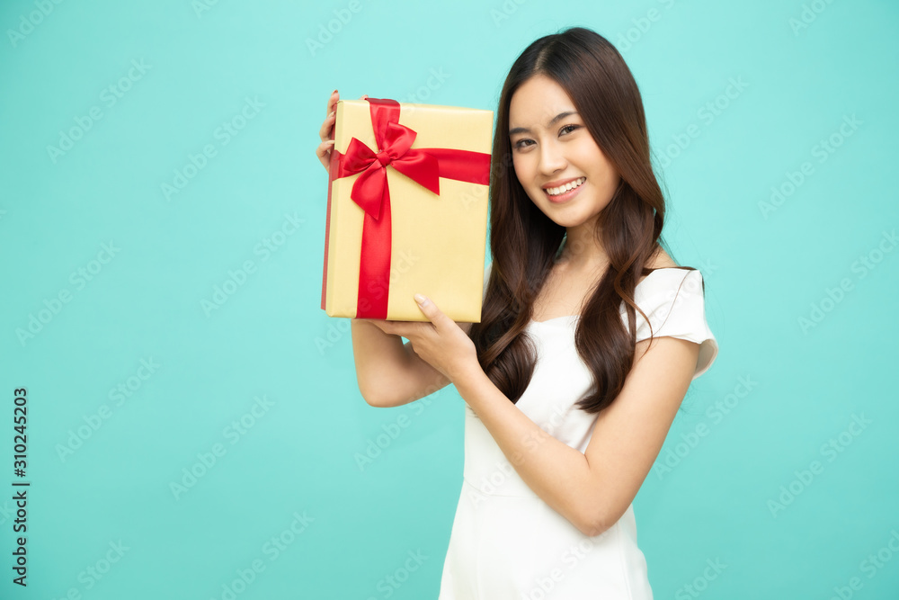 Happy beautiful asian woman smile with gold gift box isolated on light green background. Teenage girls in love, Receiving gifts from lovers. New Year, Christmas and Valentines Day concept Happy beautiful asian woman smile with gold gift box isolated on light green background. Teenage girls in love, Receiving gifts from lovers. New Year, Christmas and Valentines Day concept
