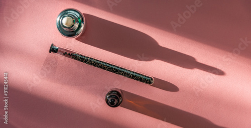 Babchi seeds in glass tube and cosmetics bottles on pink background, bakuchiol concept. photo