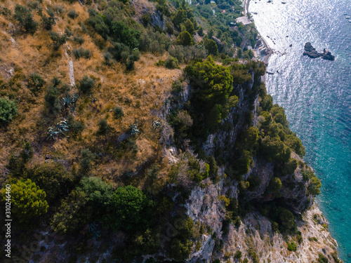 Beautiful aerial view of mountains and sea on sunset. yachts and boats stand on the raid. Trail for active sports, hiking along the mountain to a wild beach, tourist destination. Nerano bay, Italy