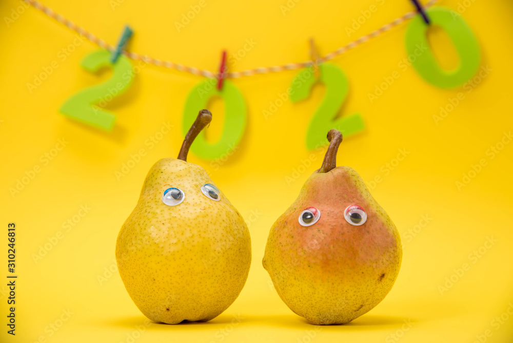 A pear isolated on yellow background with eyes celebrate the New Year 2020