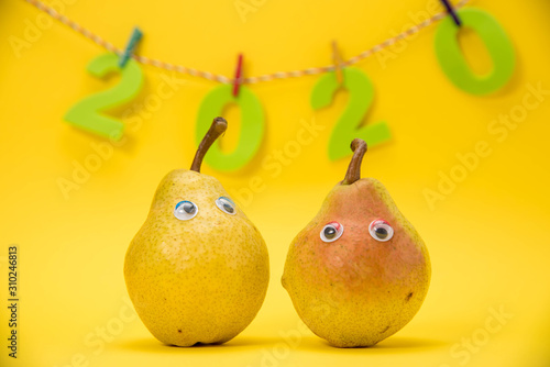 Obraz na płótnie A pear isolated on yellow background with eyes celebrate the New Year 2020 w salonie