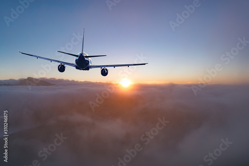 Flying of the passenger plane above the clouds and mountains.