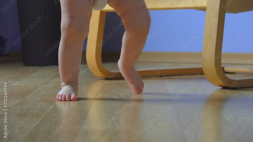 Close-up of adorable barefoot baby taking the first steps by himself