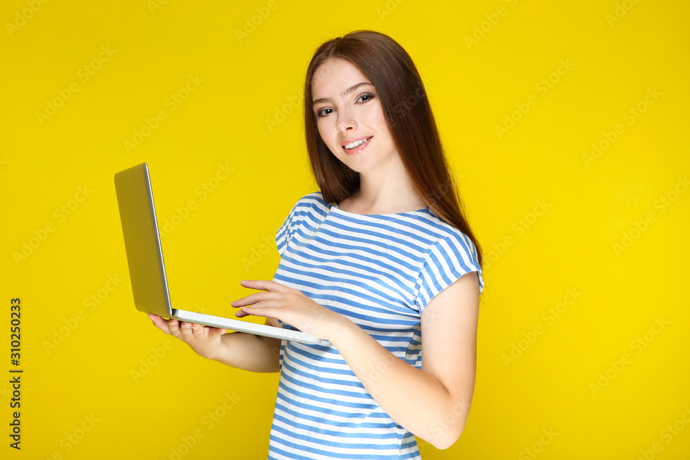 Young woman using laptop computer on yellow background Young woman using laptop computer on yellow background