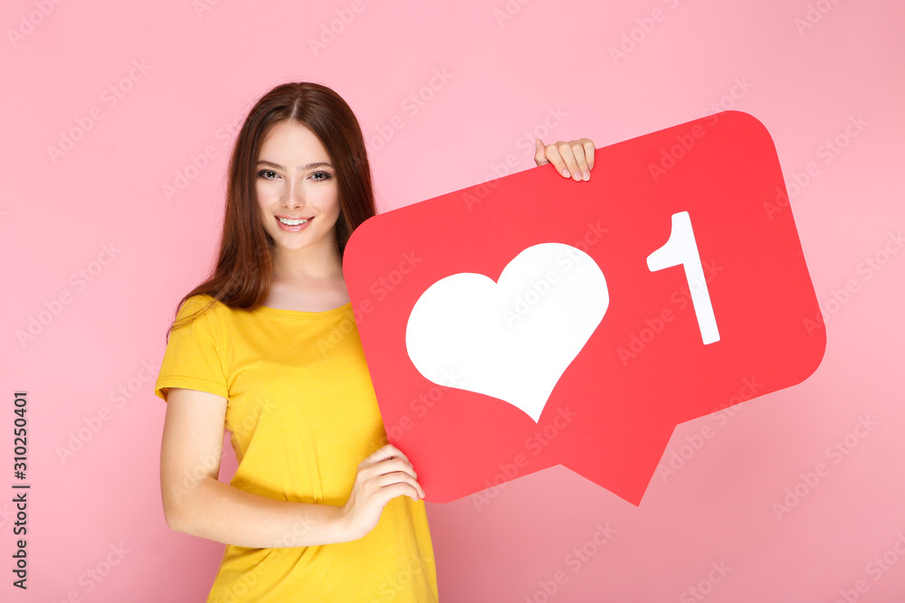 Young woman holding paper card with heart and number one on pink background Young woman holding paper card with heart and number one on pink background