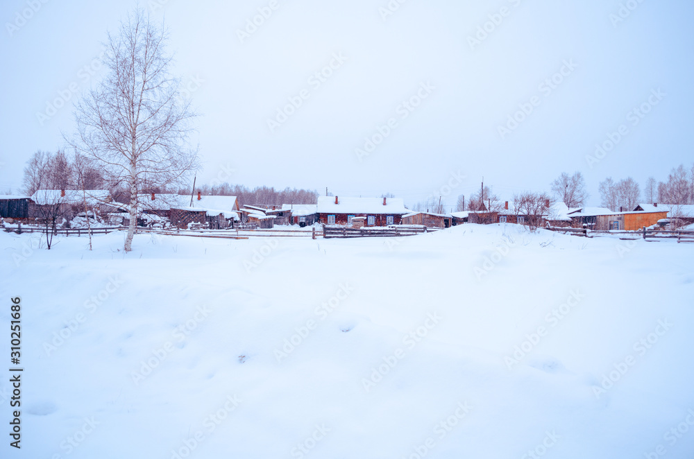 winter village in the snow on a sunny day. street of wooden houses road at houses near the forest, no people. winter village in the snow on a sunny day. street of wooden houses road at houses near the forest, no people.