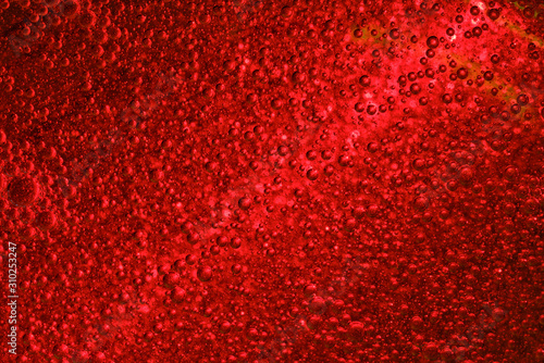 Light beam rays through three dimensional red fluid with flaying transparent bubbles.