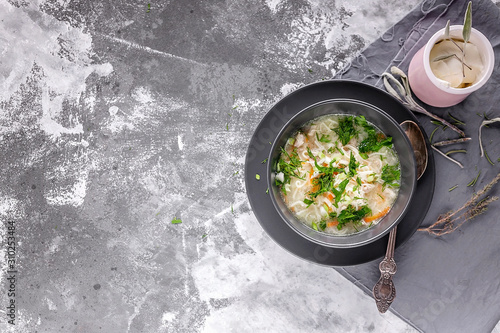 Chicken noodle soup with herbs and cheese sauce on a gray concrete background. Horizontal shot. Top view. Copy space