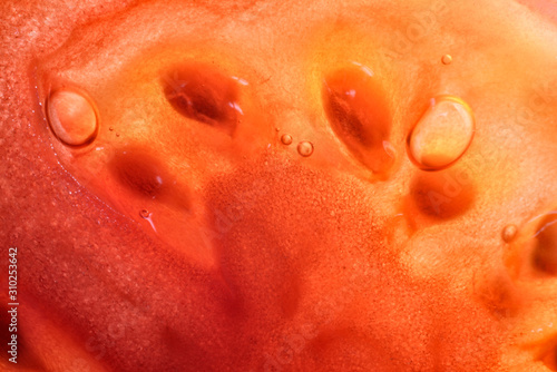 Creative, surprising macro image of tomato pulp. Abstract, fresh, fruity background with enhanced texture, fibers and seeds.
